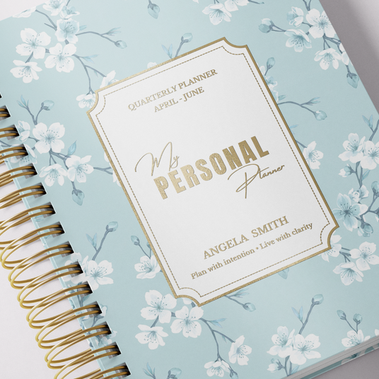 Floral-patterned planner with gold spiral binding on a light gray background